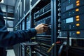 Data center room with multiple server racks. IT professional interacts with control panel of computer server. Network cables and