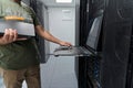 Data center technician using rack console laptop for server maintenance and IT network troubleshooting Royalty Free Stock Photo