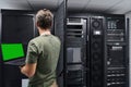 Data center technician using laptop to check server rack and network equipment in a server room Royalty Free Stock Photo