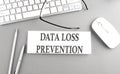 DATA LOSS PREVENTION text on paper with keyboard on grey background Royalty Free Stock Photo