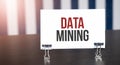 DATA MINING sign on paper on dark desk in sunlight. Blue and white background Royalty Free Stock Photo