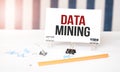 DATA MINING sign on paper on white desk with office tools. Blue and white background Royalty Free Stock Photo