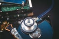 Stethoscope on dusty dismantle hard disk over dark background Royalty Free Stock Photo