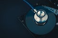 Stethoscope dusty dismantle hard disk over dark background