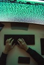 Data security. Top view of young hacker`s hands stealing data while sitting in front of monitor with binary code in dark