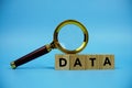 Data with wooden blocks alphabet letters and Magnifying glass on blue background Royalty Free Stock Photo