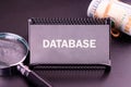 Database management tools displayed alongside a magnifying glass and currency notes on a dark surface