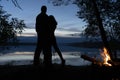 Date of a couple in love - a man and a woman in a romantic setting, on the shore by the fire, hugging and admiring the reflection