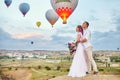 Date of a couple in love at sunset against background of balloons in Cappadocia, Turkey. Man and woman hugging standing on hill Royalty Free Stock Photo