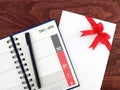 open calendar diary with date of December and January in grid and pen and envelope with red ribbon bow on desk floor Royalty Free Stock Photo