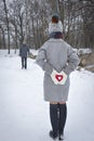 Date in the park in winter, girl holding a red heart in her hands, a gift for valentine`s day Royalty Free Stock Photo