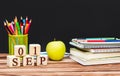 Date of 1 september on wooden cubes with school supplies and green apple on the table against blackboard. Time to back to school