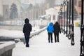 A date in the winter on the waterfront. People walk in the snow on the street. A couple in love