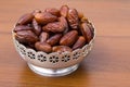 Dates fruit on silver bowl on wooden table. The Muslim feast of the holy month of Ramadan Kareem