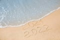 Dates written on sandy beach. 2021 washed by sea wave as New 2022 Year coming Royalty Free Stock Photo