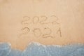 Dates written on sandy beach. 2021 washed by sea wave as New 2022 Year coming, above view Royalty Free Stock Photo