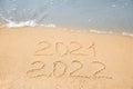 Dates written on sandy beach. 2021 washed by sea wave as New 2022 Year coming Royalty Free Stock Photo