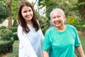 daughter or caregiver Take an elderly mother for a walk in an outdoor park, both smiling happily. Royalty Free Stock Photo