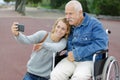 daughter and dad sitting in wheelchair taking selfie Royalty Free Stock Photo