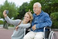 daughter and dad sitting in wheelchair taking selfie Royalty Free Stock Photo