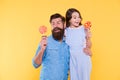 Daughter and father eat sweet candy. Bearded man and cute sweet baby. Loving daddy and small girl eating lollipop