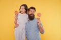 Daughter and father eat sweet candy. Bearded man and cute sweet baby. Loving daddy and small girl eating lollipop