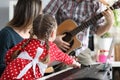 Daughter, father and mother play musical instruments, guitar, pionino together Royalty Free Stock Photo