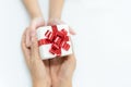 Daughter gives a gift to mother. White box with red bow in the girl hands and mother