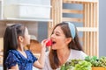 Daughter gives a red apple to her mother, mother, and daughter cook together in the kitchen, Happiness family concepts Royalty Free Stock Photo