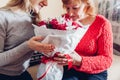 Daughter giving her mother bouquet of flowers at home as Mother& x27;s day present. Senior woman smelling roses Royalty Free Stock Photo