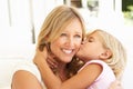 Daughter Giving Mother Kiss Relaxing On Sofa