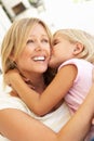 Daughter Giving Mother Kiss Relaxing On Sofa