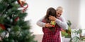 Daughter giving present to happy mother and embrace indoors at home at Christmas Royalty Free Stock Photo