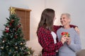 Daughter giving present to happy mother and embrace indoors at home at Christmas Royalty Free Stock Photo