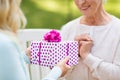 Daughter giving present to senior mother at park Royalty Free Stock Photo