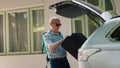 Daughter and grandparents loading voyage luggage inside car trunk Royalty Free Stock Photo