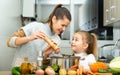 Daughter helping cooking soup and mother add pepper to pan Royalty Free Stock Photo