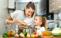 Daughter helping cooking soup and mother add pepper to pan Royalty Free Stock Photo