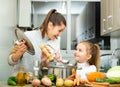 Daughter helping cooking soup and mother add pepper to pan Royalty Free Stock Photo