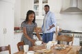 Daughter Helping Father To Clear Table After Family Meal