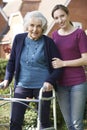 Daughter Helping Senior Mother To Use Walking Frame