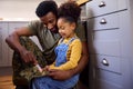 Daughter Holding Cap Of American Army Father In Uniform Home On Leave In Family Kitchen Royalty Free Stock Photo