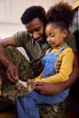 Daughter Holding Cap Of American Army Father In Uniform Home On Leave In Family Kitchen Royalty Free Stock Photo