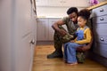 Daughter Holding Cap Of Army Father In Uniform Home On Leave In Family Kitchen Royalty Free Stock Photo