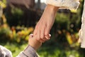 Daughter holding mother`s hand outdoors, closeup view Royalty Free Stock Photo
