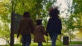 Daughter holding parents walking green park path rear view. Joyful leisure time Royalty Free Stock Photo