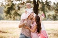 The daughter hugging parents on nature. Mom, dad and girl toddler, walk in the park. Happy young family spending time Royalty Free Stock Photo