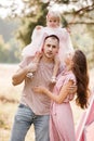 The daughter hugging parents on nature. Mom, dad and girl toddler, walk in the park. Happy young family spending time Royalty Free Stock Photo