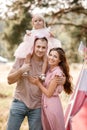 The daughter hugging parents on nature. Mom, dad and girl toddler, walk in the park. Happy young family spending time Royalty Free Stock Photo