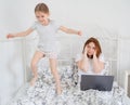 Daughter interferes to work mom in bed. quarantine Royalty Free Stock Photo